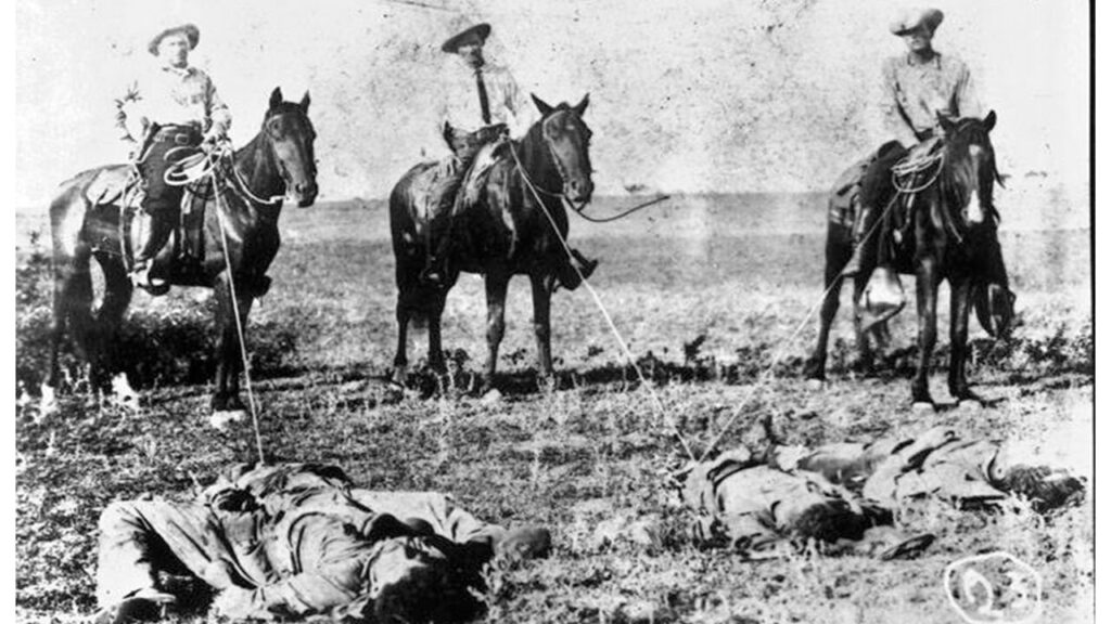 From left to right Ranger captain James Monroe Fox, ranch foreman and Special Ranger Tom Tate, and an unidentified rider standing over the bodies of three Mexicans who participated in the King Ranch raid on August 8, 1915. This postcard and others like it were sold in drugstores and tobacco shops across South Texas. (Credit: Negative #073-0473, General Photograph Collection, UTSA Special Collections.